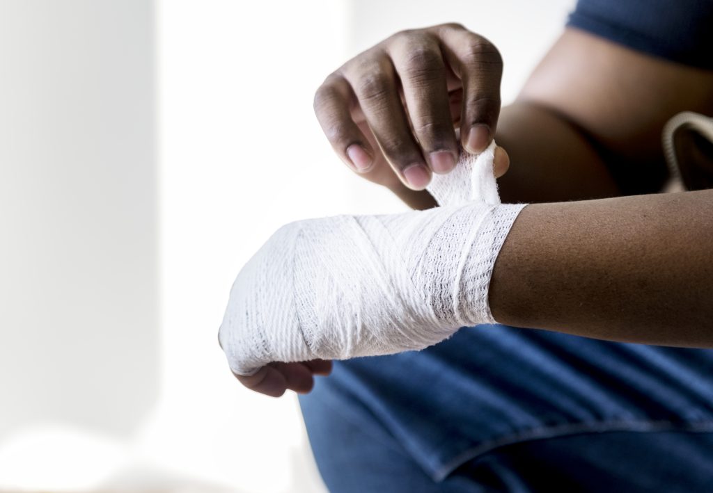 Image of an arm with a white cloth bandage wrapped around the hand