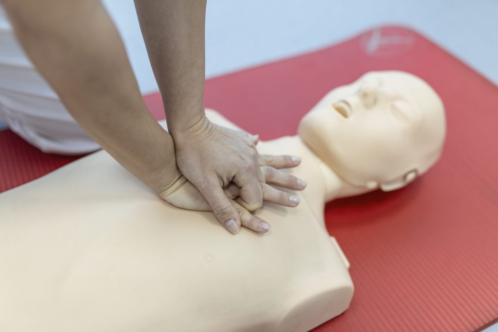 Image showing a CPR class in progress, with a participant practicing chest compressions on a mannequin.