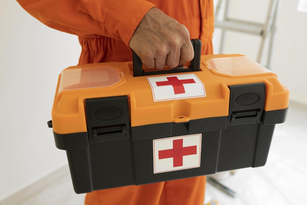 Image of a man's arm carrying a black and orange plastic emergency first aid kit.